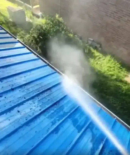 Water spraying across a blue metal roof panel